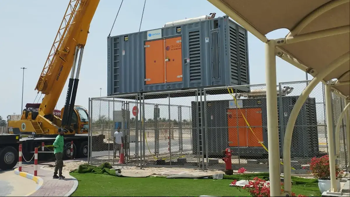 Crane lifting a SINTAQA containerised rental generator into position on site