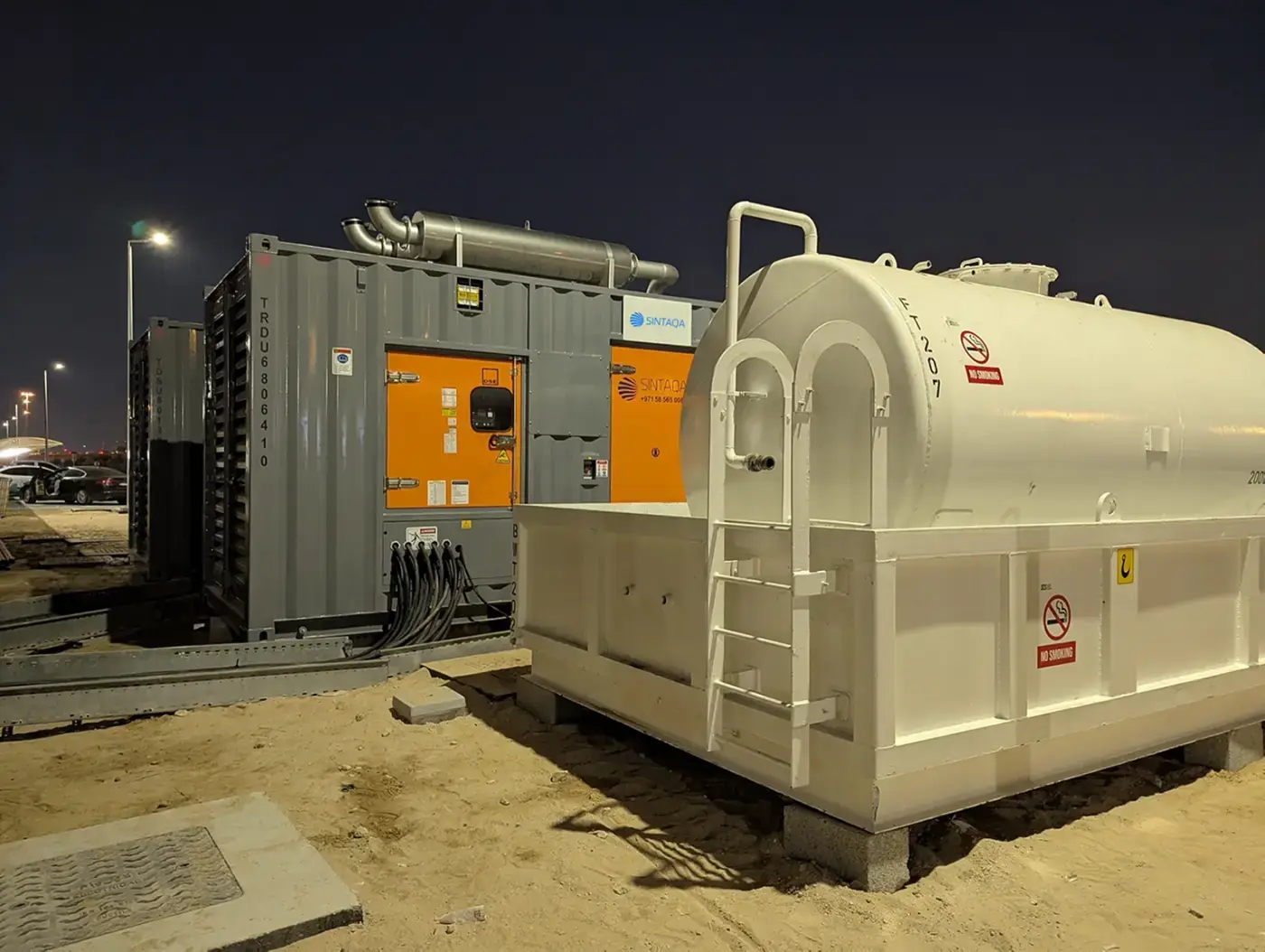 SINTAQA containerised generator and bulk fuel tank operating at night on a project site